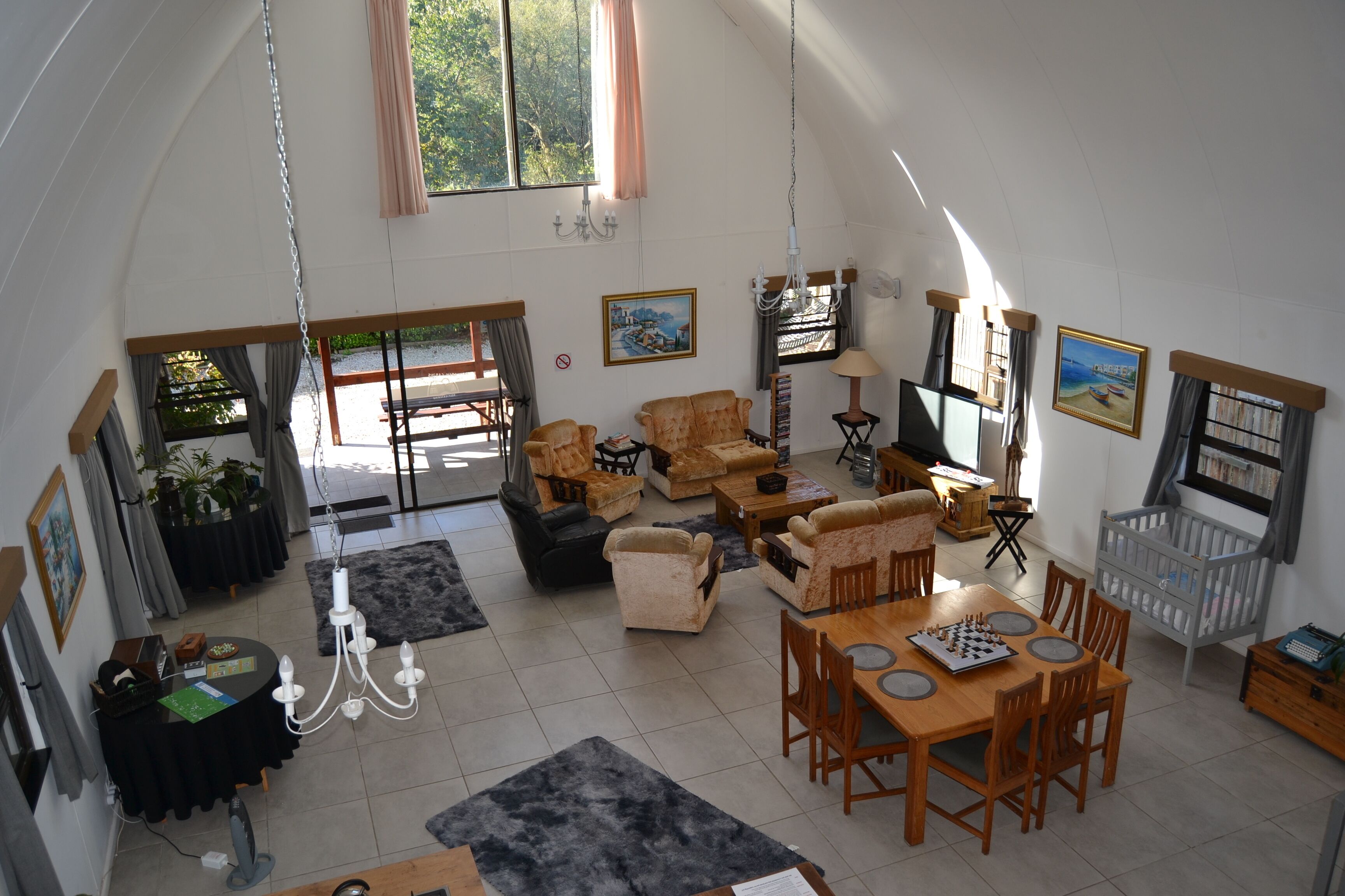 A spacious living room with multiple seating areas, a dining table, and a crib.