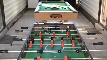 A room with two foosball tables, a pool table, and a billiards table.