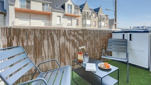 A patio area with a table set for two, a chair, a bottle, and a glass. - l'Emérillon - Appt à 200m de la plage (Saint-Cast-le-Guildo)
