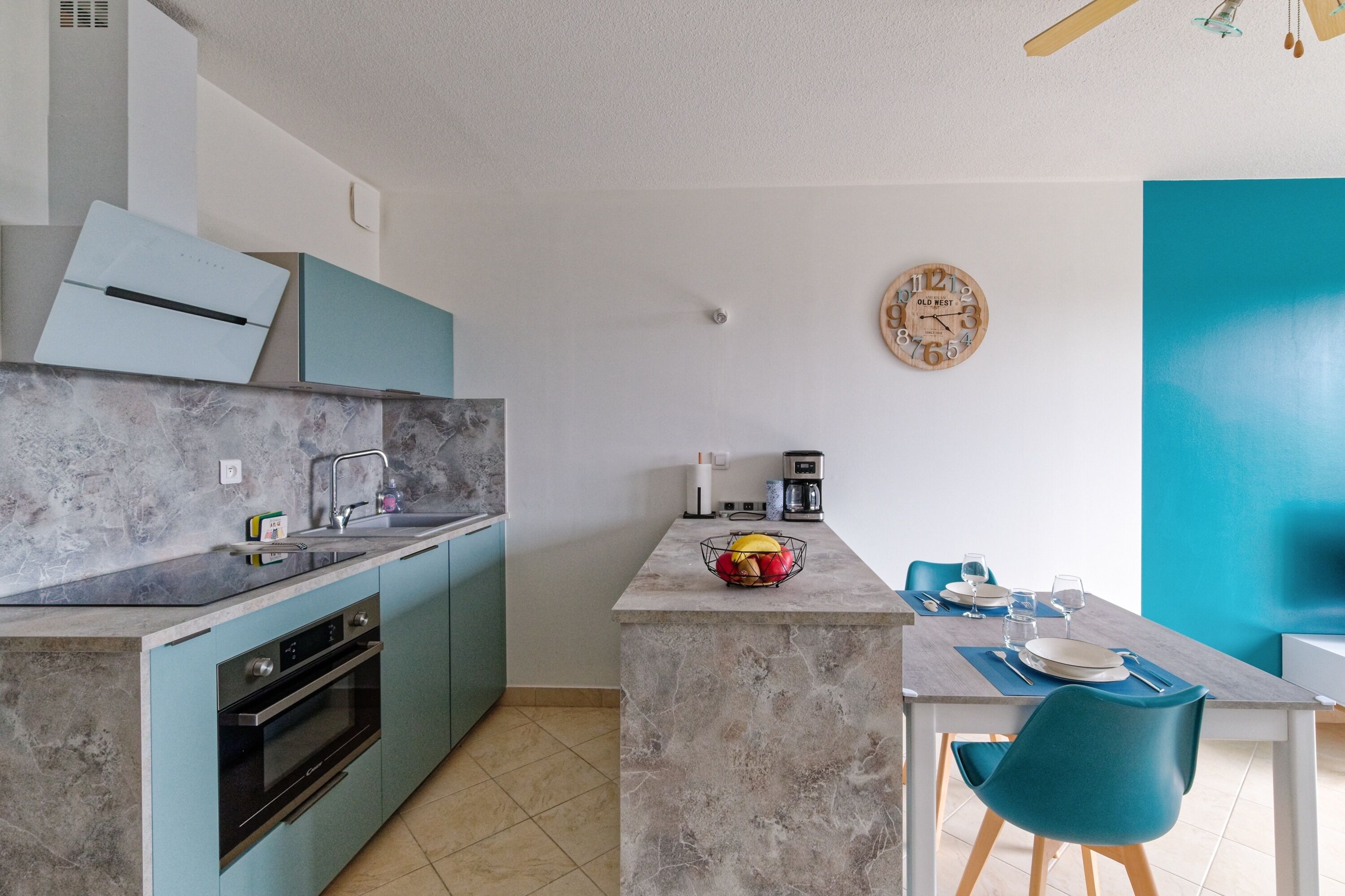 Une cuisine moderne dotée d’un plan de travail en marbre, d’un four encastré et d’un coin repas avec une table et des chaises.