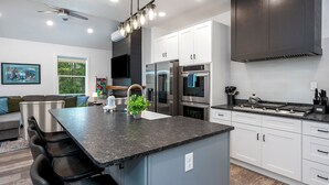 Een moderne keuken met een centraal eiland, roestvrijstalen apparatuur en een plafondventilator.