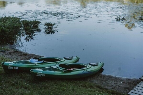 Two green kayaks parked by a calm body of water with a grassy bank. - Little Blue Lake Front Cottage + Hot Tub (Greenville)