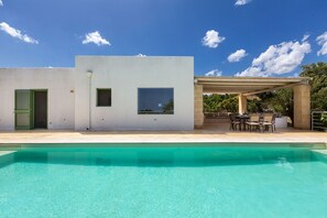 Un bâtiment moderne doté d’une piscine, d’un espace extérieur aménagé et d’une pergola.