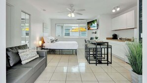 A modern, well-lit room with a bed, a sofa, a dining area, and a kitchen. - Sunlit Studio Escape: Hollywood Haven, sleeps 4! (Hollywood)