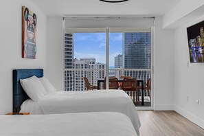 Enjoy a city view from the comfort of your room, featuring a large bed, balcony with outdoor seating, and a window with a view of the city.