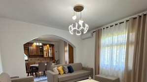 A modern living room with a sofa, coffee table, and a dining area in the background. - Family - sized villa , pet friendly , city and castle view with a big garden ! (Berat)