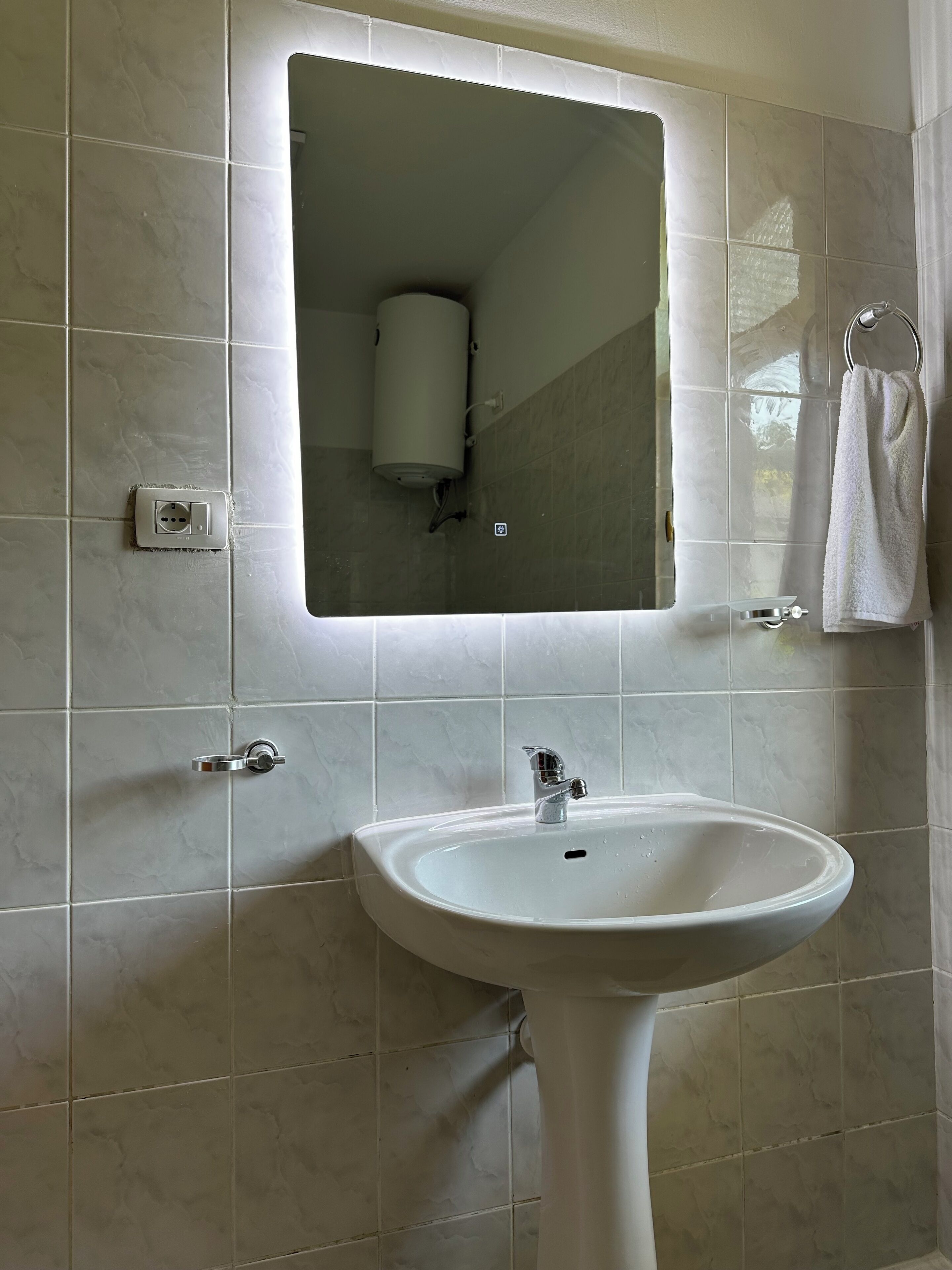 A bathroom with a white sink, a mirror, and a towel rack.