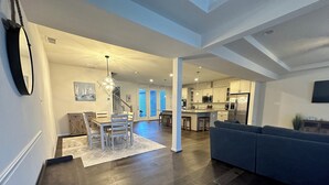 A modern open-plan living space with a dining area, kitchen, and a staircase leading to an upper level.