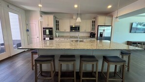 A modern kitchen with granite countertops, stainless steel appliances, and wooden bar stools.
