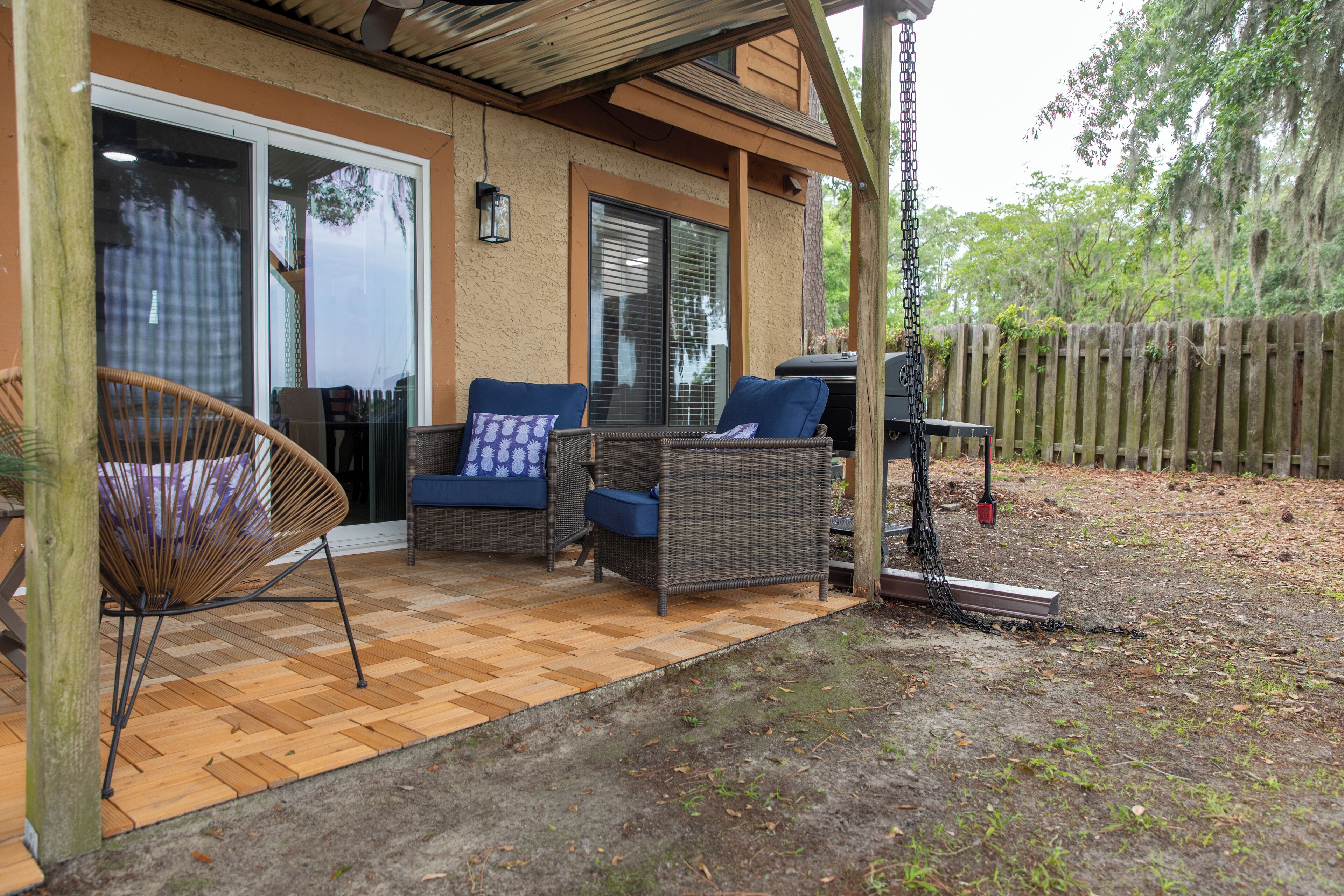 An outdoor patio with wicker furniture, a barbecue grill, and a wooden deck.