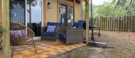 An outdoor patio with wicker furniture, a barbecue grill, and a wooden deck.