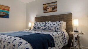 A neatly made bed with patterned bedding and a pillow with the text "STAY awhile". - Romantic Waterfront Getaway
 1st Floor Deep Water Views (Beaufort)