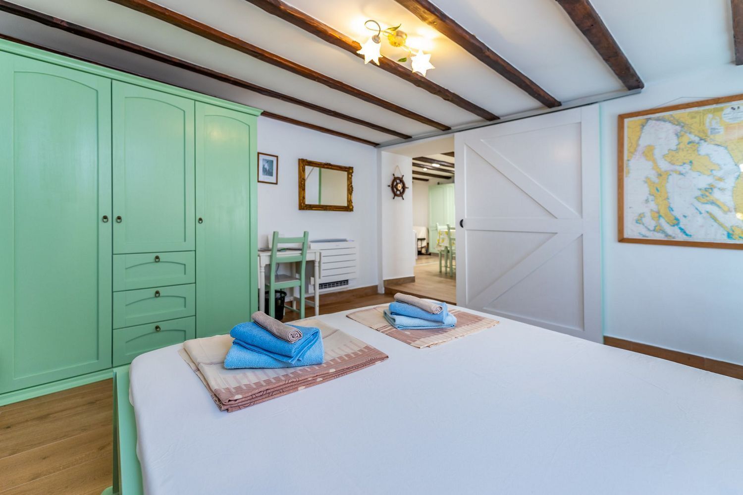 Een kamer met een bed, een groene garderobe, een bureau met stoel, en een kaart aan de muur.