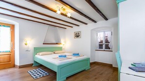 A bedroom with a bed, wooden beams, a window, and a door. - Almost directly on the beach in the old town with many alleyways (Baska)