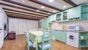 A compact kitchen with teal cabinets, a washing machine, and a dining area with a table and chairs. - Almost directly on the beach in the old town with many alleyways (Baska)