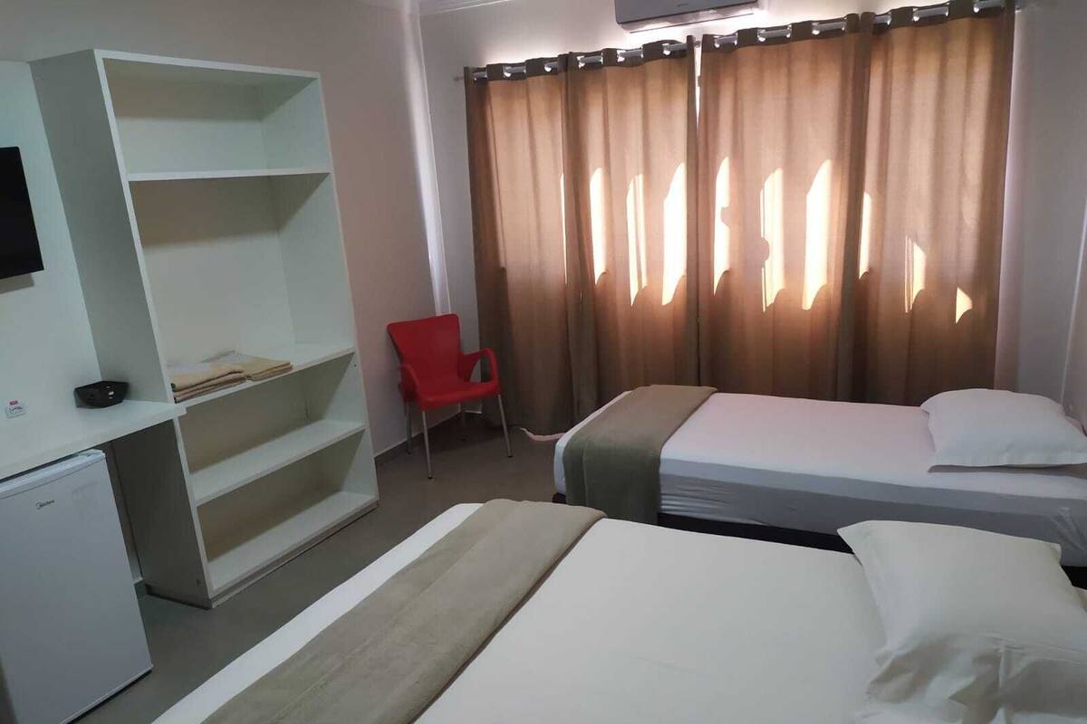 A hotel room with a bed, a desk with a chair, and a wardrobe.