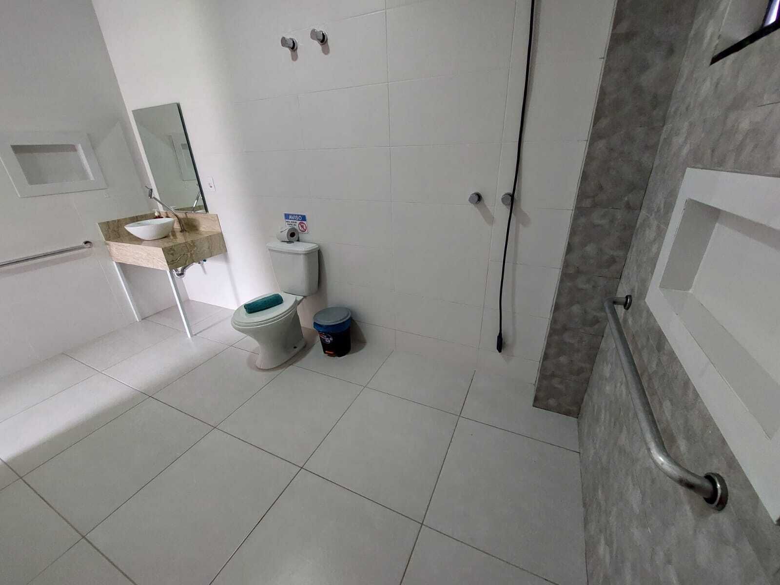 A bathroom with a toilet, sink, mirror, and shower area.