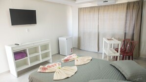 A hotel room with a bed, a TV mounted on the wall, a small desk with a chair, and a window with curtains. - POUSADA CASTELO DO REI (Penha)