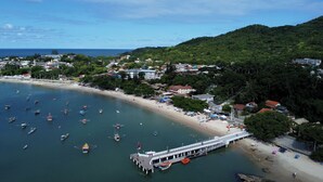 An aerial view of a coastal town with a pier, boats, and a beach. - POUSADA CASTELO DO REI (Penha)