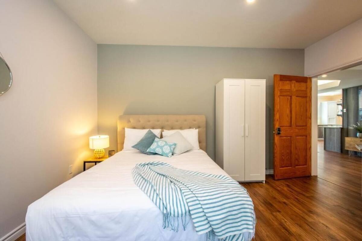 Ein Schlafzimmer mit Bett, Nachttischlampe, Kleiderschrank und Holztür.