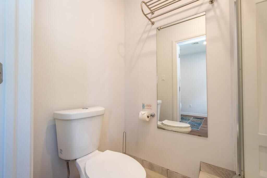 Un baño pequeño y limpio con inodoro, secamanos y espejo.
