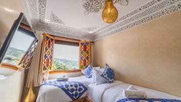 Een hotelkamer met een bed, een raam met uitzicht en ingewikkelde plafonddecoraties.