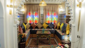Ein Zimmer mit einer gemusterten Couch, einem Ziertisch und einer Chandelüster.