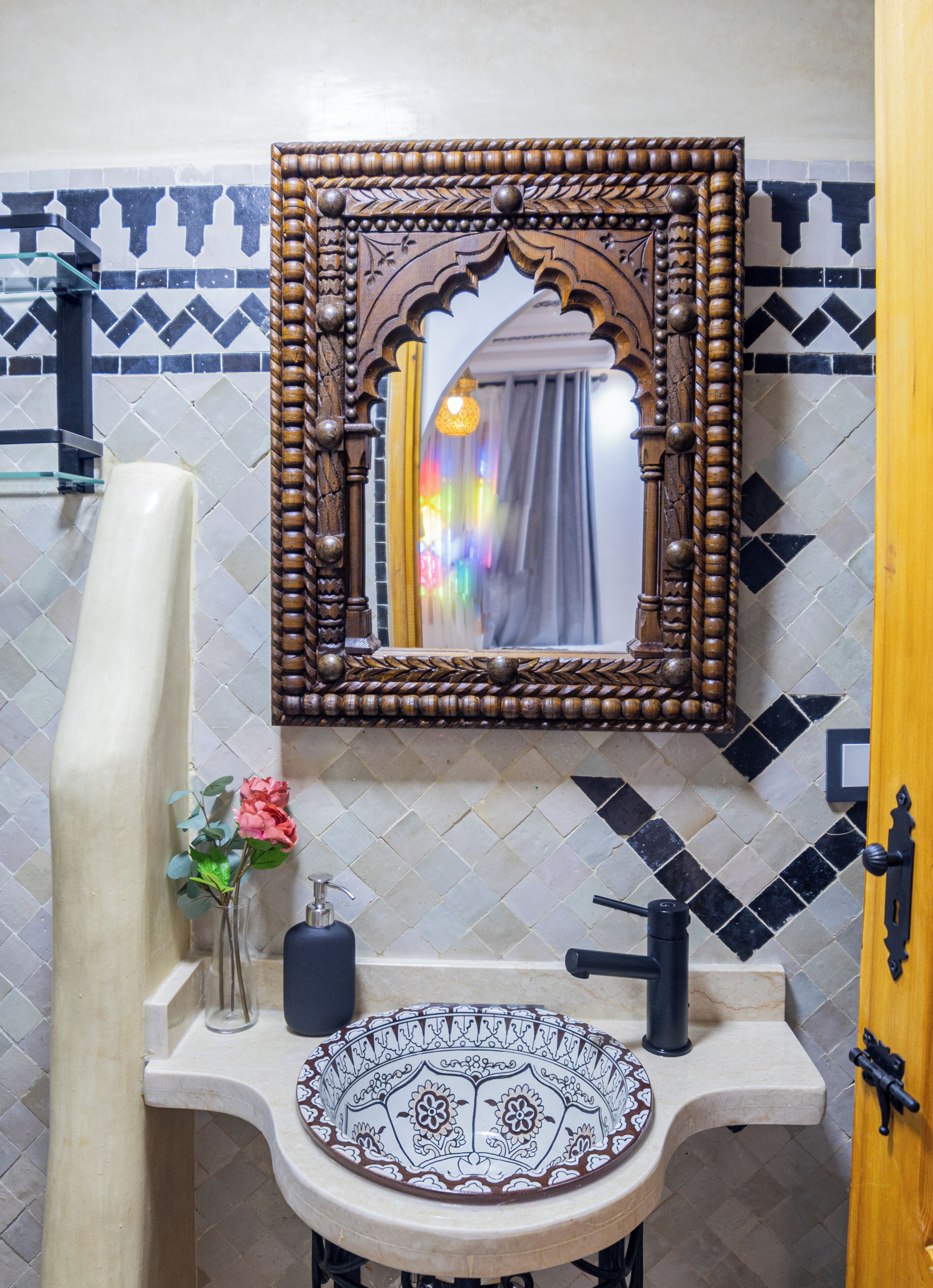 A bathroom with a decorative mirror, a sink with a patterned basin, and a towel rack.