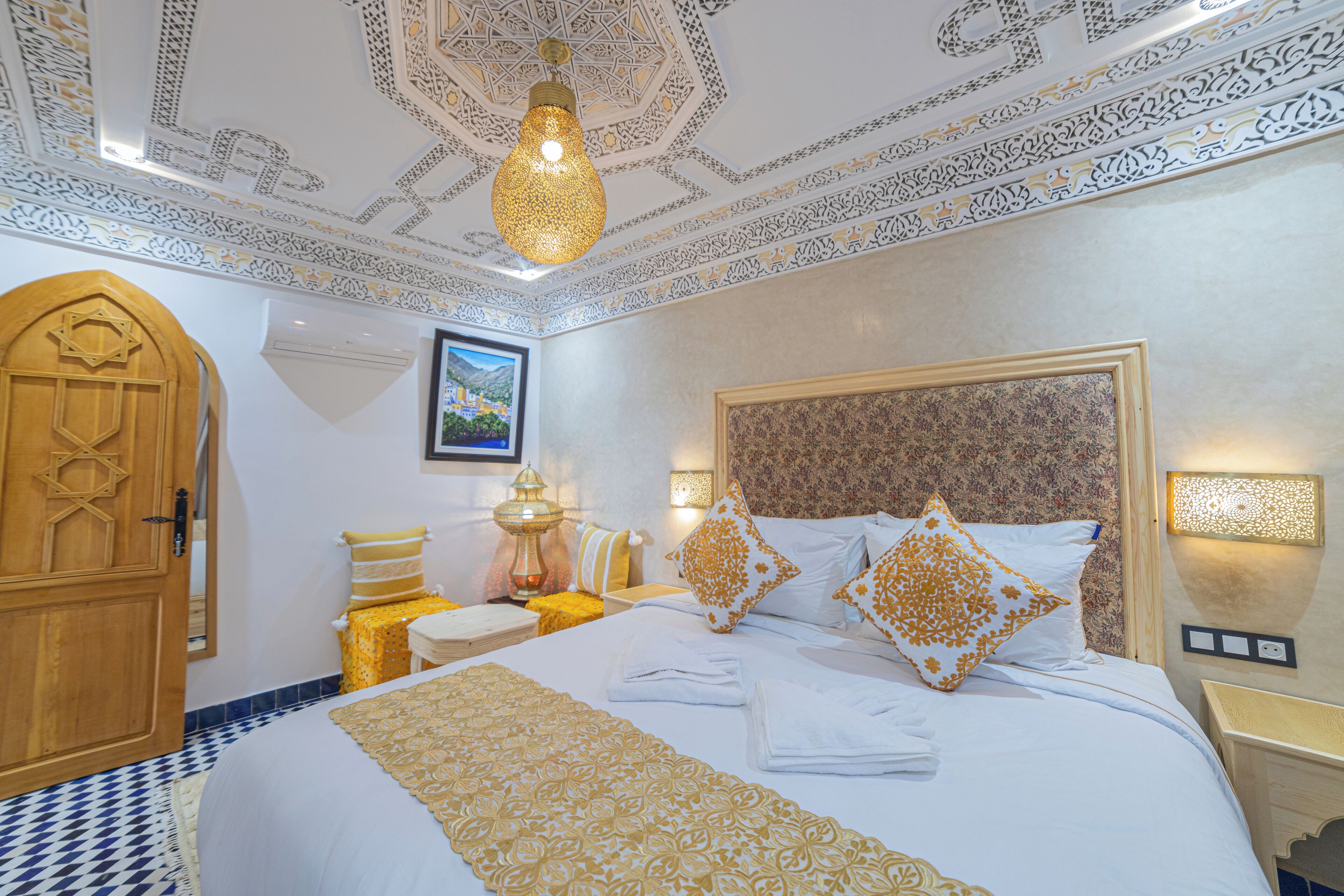 Ein stilvoll eingerichtetes Hotelzimmer mit einem großen Bett, einer verzierten Decke und einer Holztür mit Davidstern.