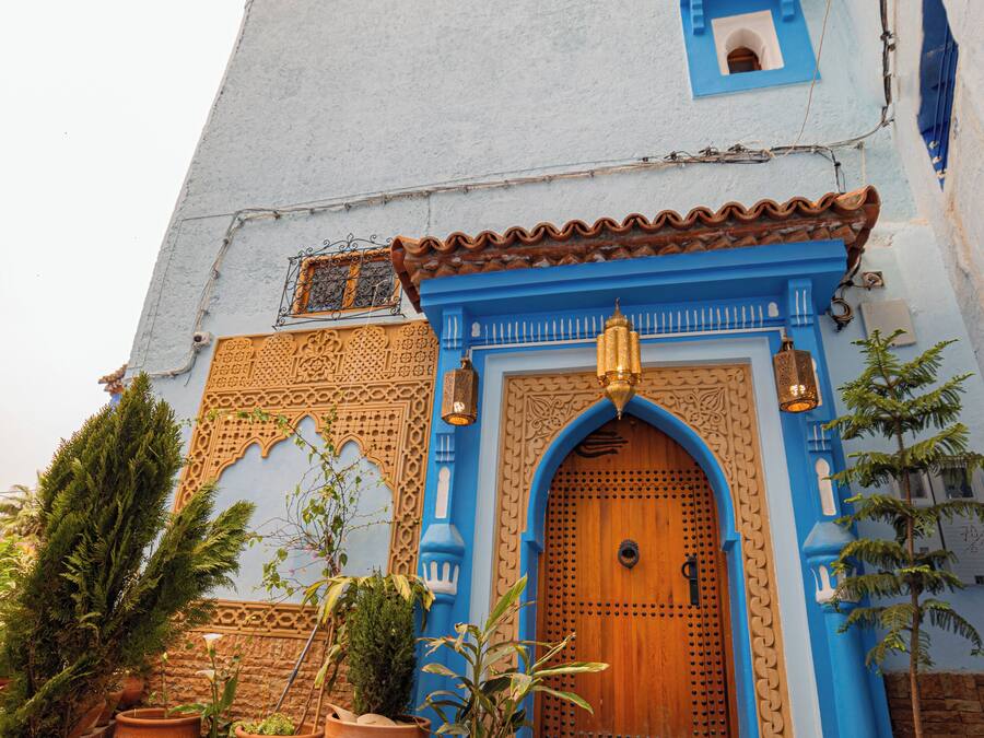 A building with a blue facade, a wooden door, and terracotta pots.