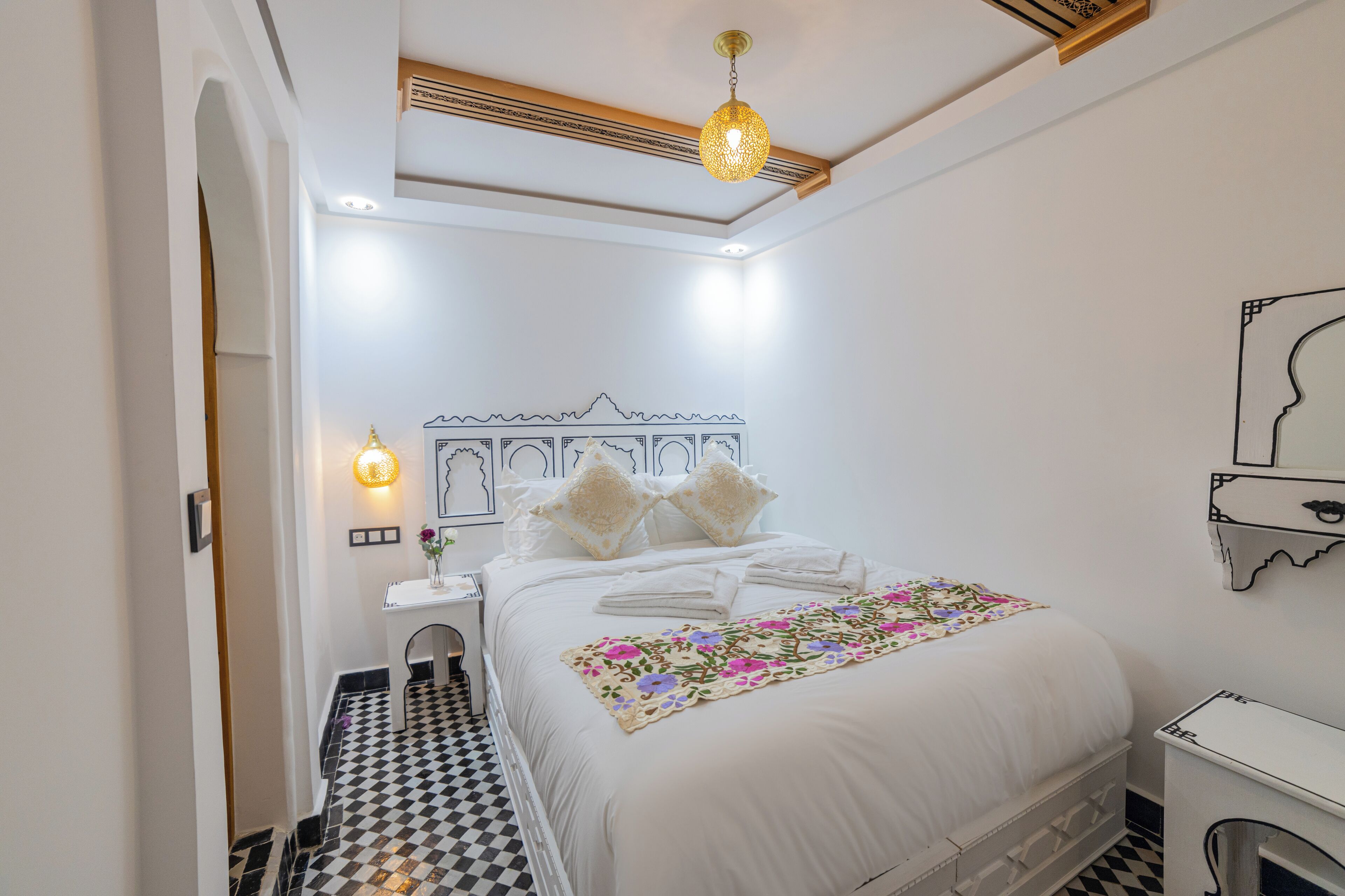 A neatly arranged bedroom with a bed, bedside table, and a small desk.