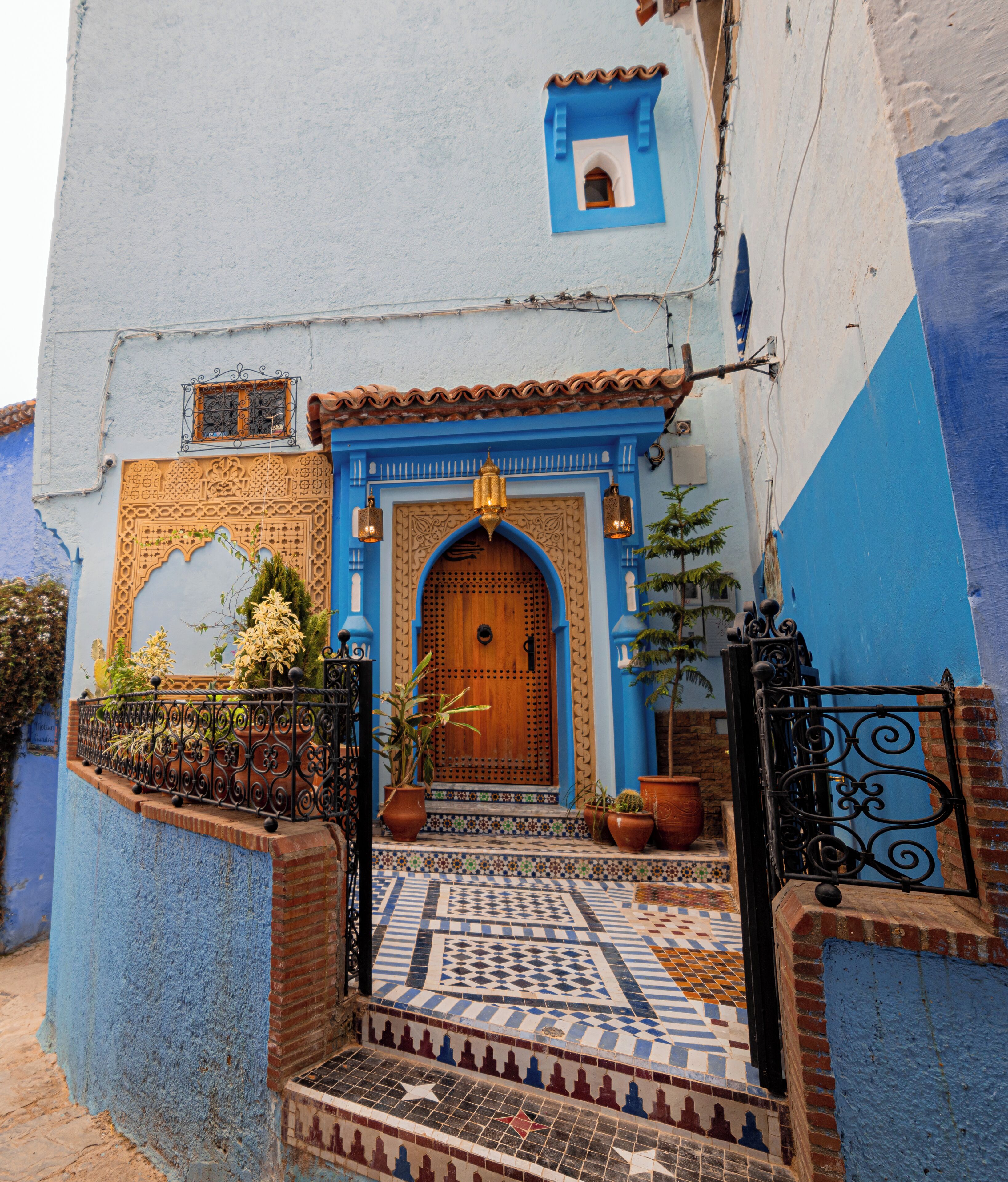 A traditional Moroccan house with a wooden door, blue and white walls, and a tiled entrance.
