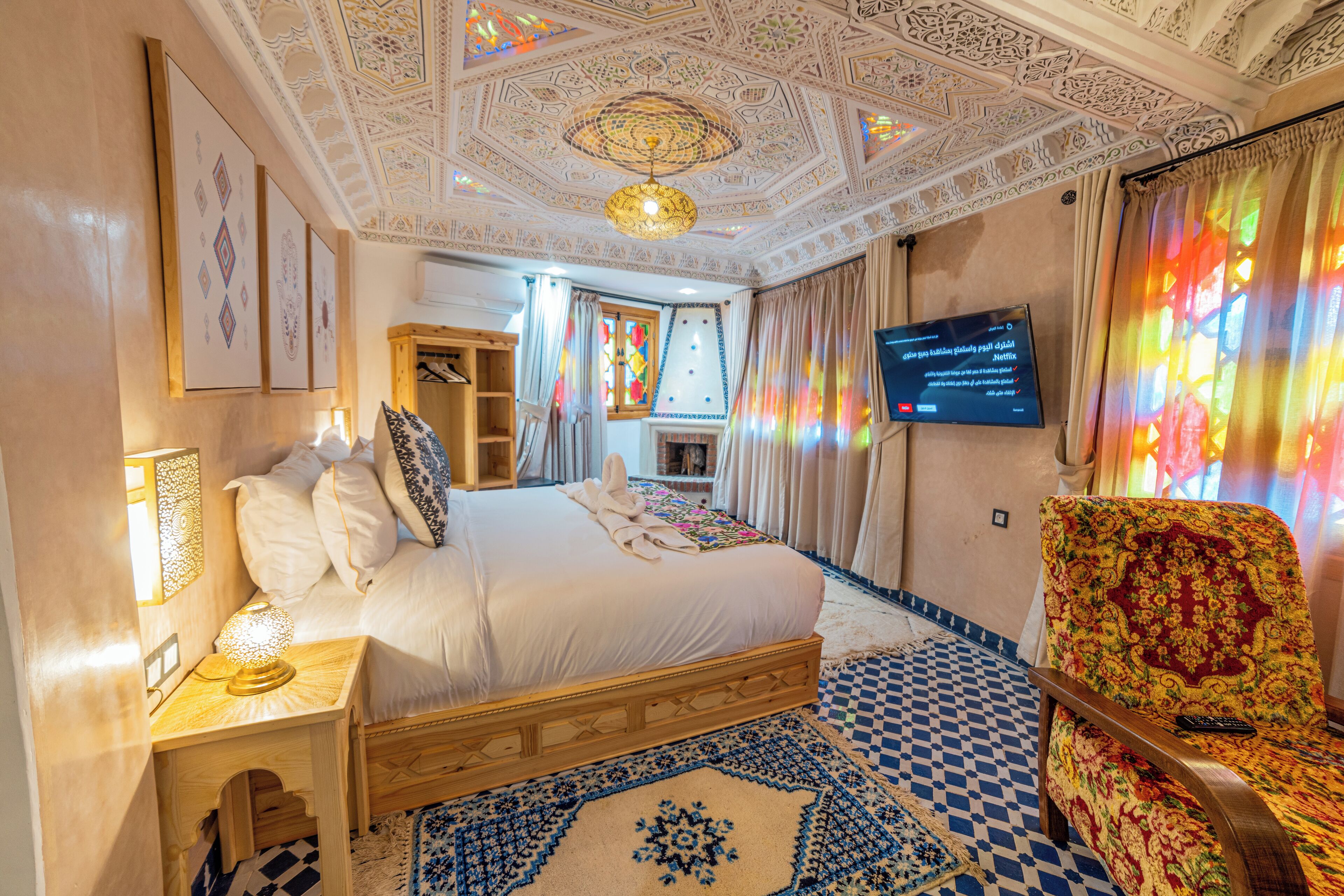 Habitación de hotel con una cama grande, un televisor, un tapete estampado y un techo decorativo.