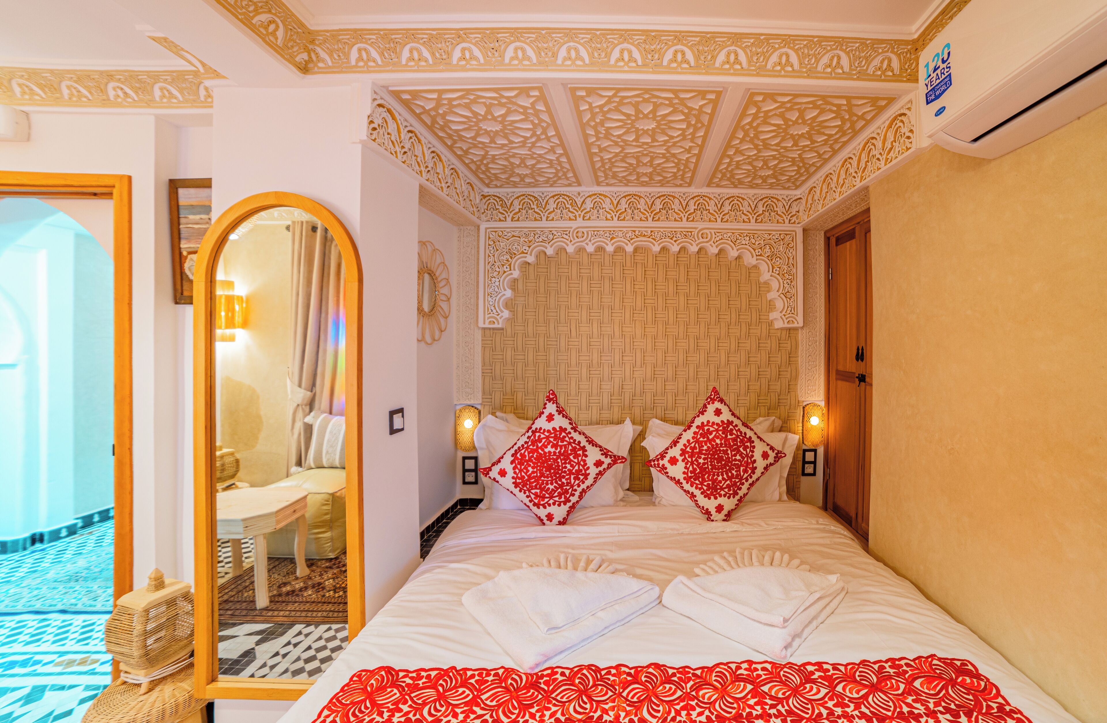 Une chambre d’hôtel avec un grand lit, un plafond décoratif et un miroir.