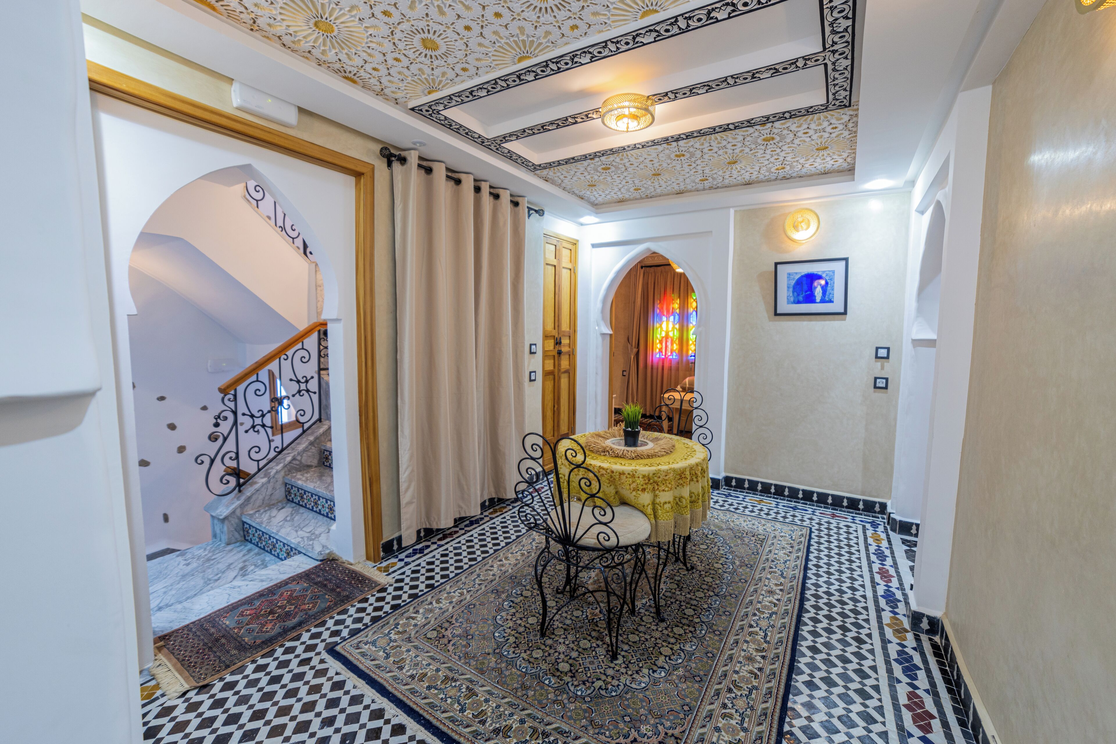 A hallway with a staircase, a dining area with a table and chairs, and a decorative ceiling.
