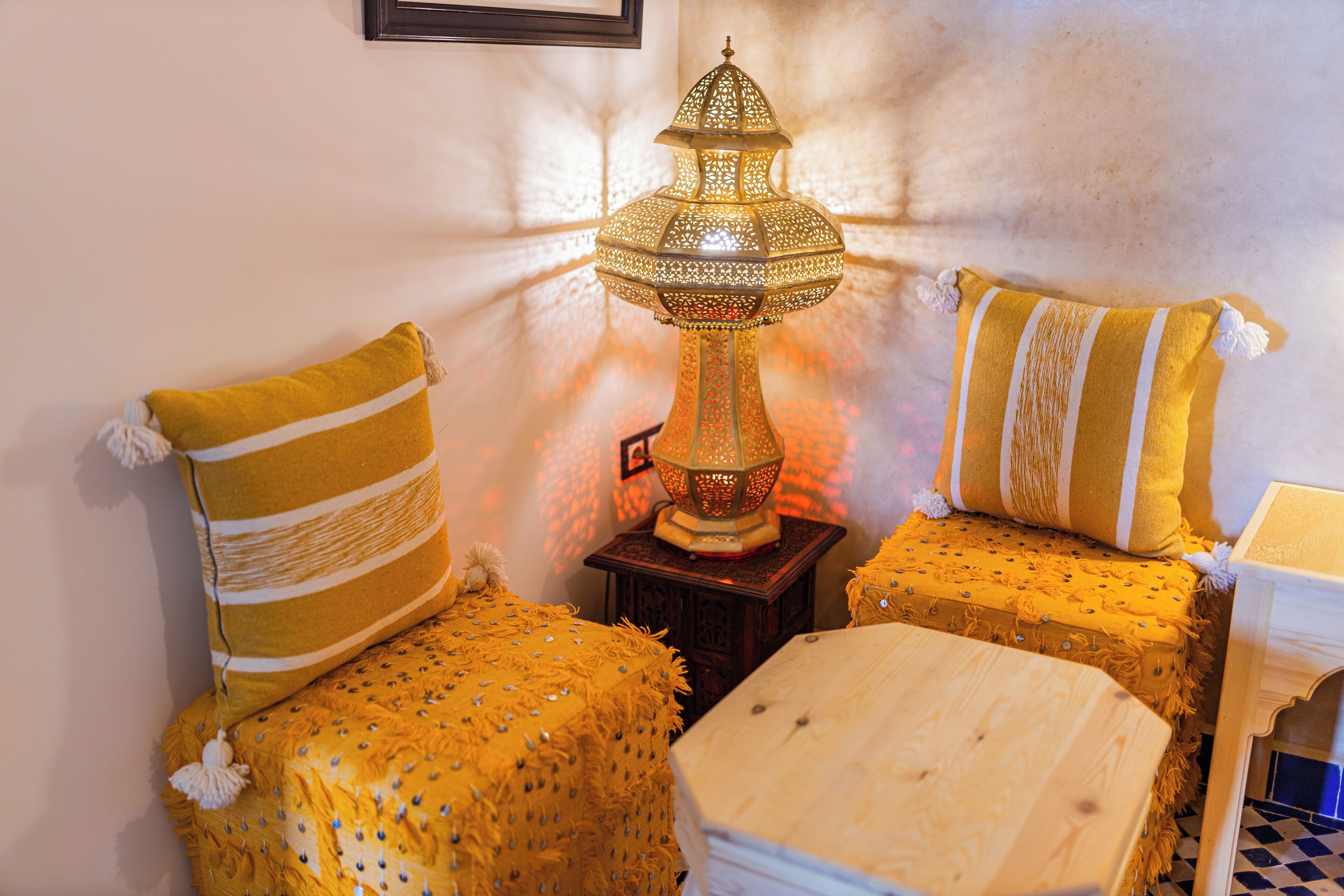 Une pièce avec une lampe de style traditionnel, deux canapés jaunes à motifs et une petite table en bois.