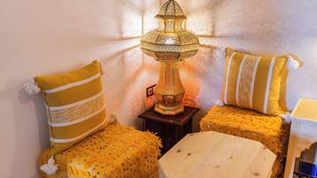 Une pièce avec une lampe de style traditionnel, deux canapés jaunes à motifs et une petite table en bois.