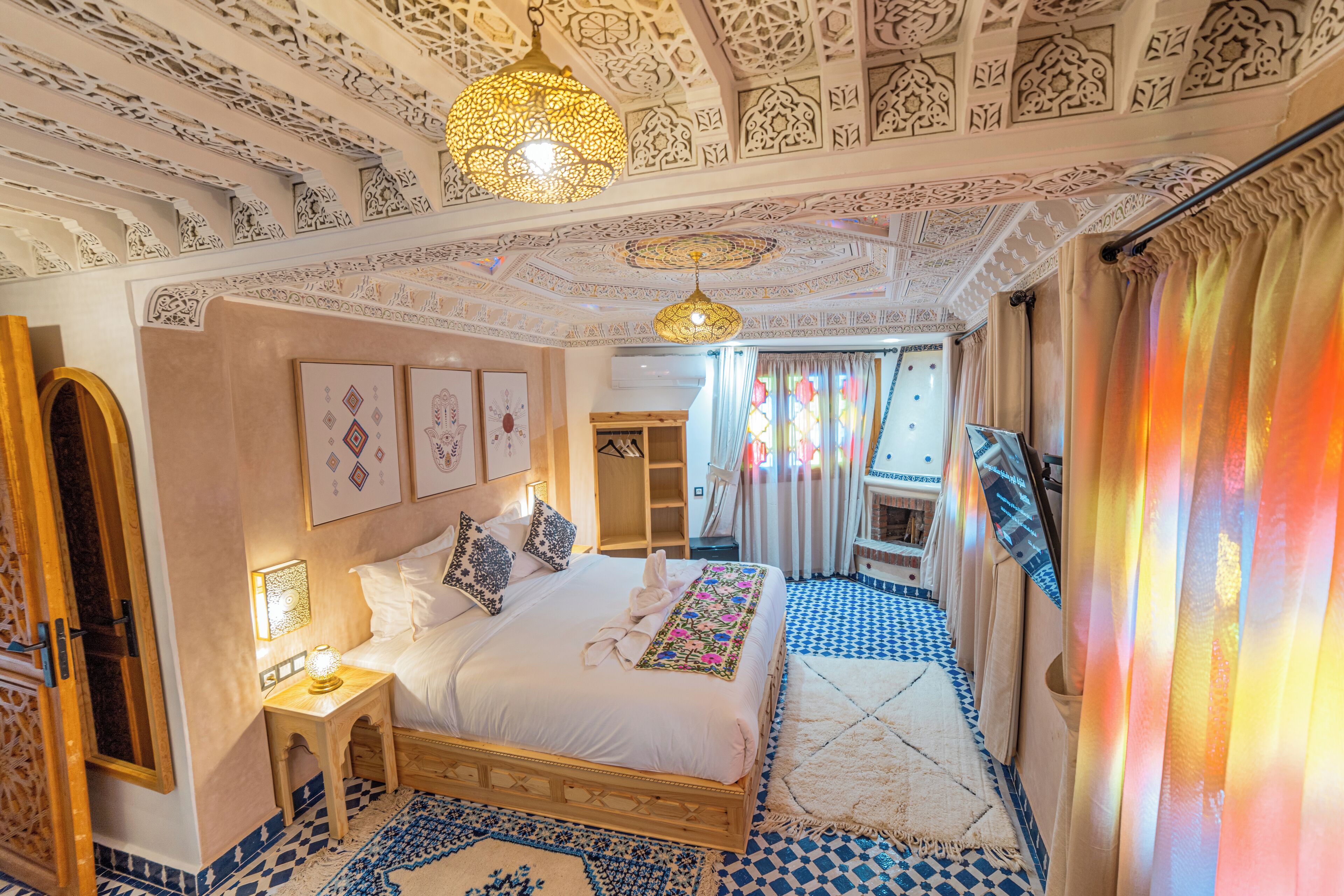 A room with a large bed, ornate ceiling, and patterned floor tiles.