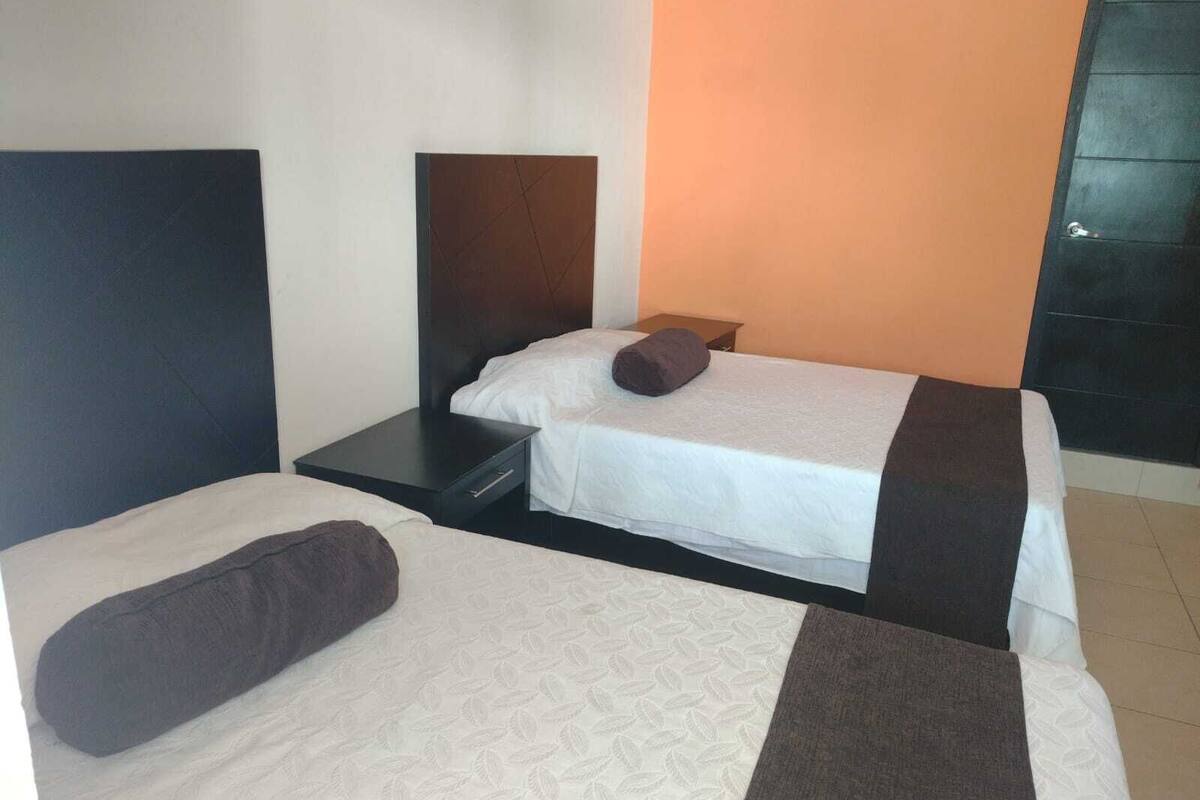 A hotel room with two beds, a nightstand, and a dresser.