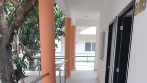 A corridor with orange pillars, a tiled floor, and black doors. - Hotel Centro Valles  (Ciudad Valles)