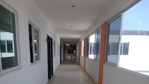 A long, narrow corridor with tiled floors and large windows on both sides. - Hotel Centro Valles  (Ciudad Valles)