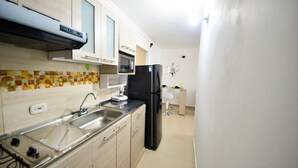 Une cuisine équipée d’une cuisinière à gaz, d’un évier en acier inoxydable, d’un four à micro-ondes et d’un réfrigérateur noir.