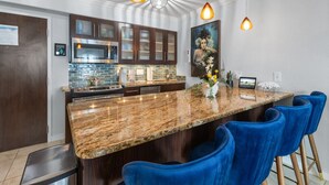 Une cuisine moderne dotée d’un grand îlot central, de meubles de rangement en bois foncé et de tabourets de bar bleus.