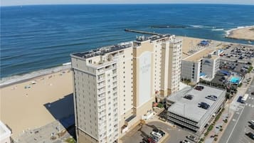 A high-rise hotel with multiple floors, a parking area, and a beach view.