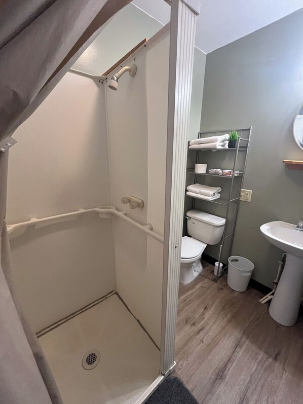Un bagno con doccia, toilette, lavandino e scaffali.