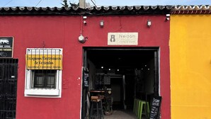 A red and yellow building with a sign for Neizan Hotel & Cafe. - NEIZAN HOTEL (Antigua Guatemala)