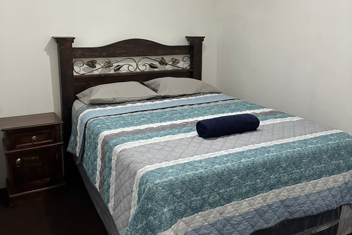 Un dormitorio con cabecera de cama de madera, una mesita de noche y una lámpara en el techo.