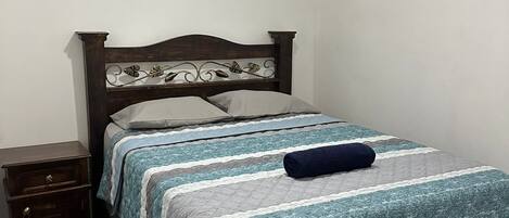 A bedroom with a wooden bed frame, a nightstand, and a ceiling light fixture.