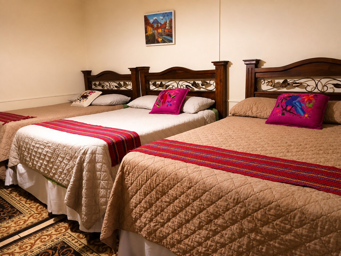 Een hotelkamer met drie bedden, elk met een andere hoofdbordstijl en kussens.
