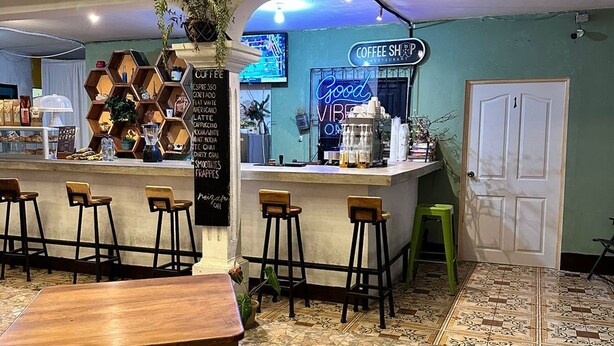 A coffee shop with a counter, stools, and a patterned floor. - NEIZAN HOTEL (Antigua Guatemala)